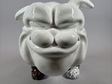 a white ceramic sculpture of a dog with a ball in it ' s mouth