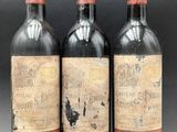 three bottles of red wine sitting next to each other on a table
