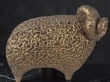 a gold statue of a ram on a black surface