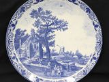 une assiette bleue et blanche sur laquelle est représentée une scène de vie à la ferme