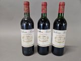 three bottles of red wine sitting on a table next to each other