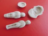 three small white figurines on a red surface with a red background