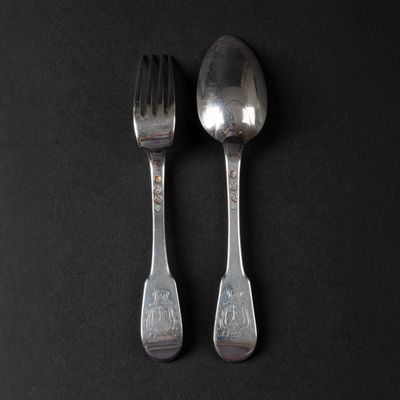 two spoons and a fork on a black surface