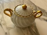 a white and gold teapot sitting on a marble table