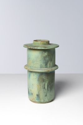un gros plan d'un vase vert posé sur une surface blanche