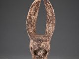 une sculpture marron représentant une tête d'animal sur une surface grise