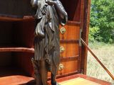 une statue représentant une femme debout devant une bibliothèque