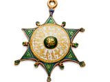 un gros plan d'une médaille en forme d'étoile ornée d'un motif vert et or