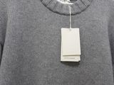 the sweater is hanging on a hanger with a tag on it