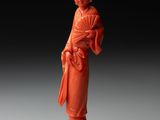 une figurine en jade orange représentant une femme tenant un éventail