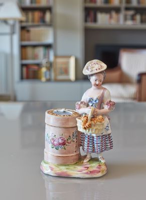 a figurine of a woman with a basket of flowers on a table