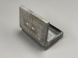 une vieille boîte en argent portant une inscription, posée sur une table