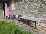 des tables et des chaises devant un bâtiment en pierre, avec des parasols en arrière-plan