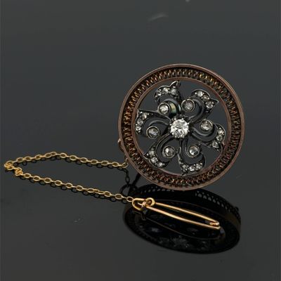 a close up of a gold and diamond broochle on a chain
