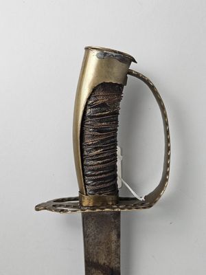 une vieille épée avec une poignée en métal sur une surface blanche
