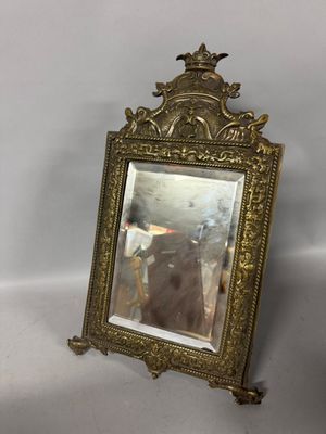 an antique brass framed mirror with a bird on top of it