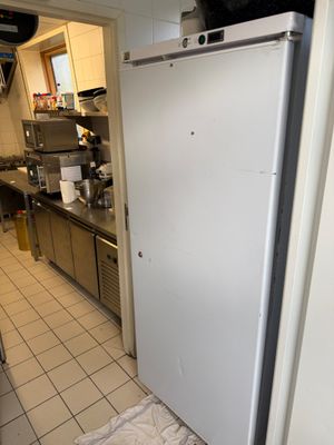 un réfrigérateur blanc dans une cuisine, avec un chat noir posé dessus
