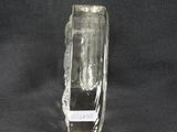 a clear glass vase with a black base on a black background