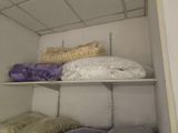 many pillows and blankets on the shelves in the closet