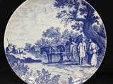 une assiette bleue et blanche sur laquelle est représentée une calèche