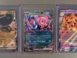 trois cartes Pokémon différentes, rangées dans des pochettes en plastique, posées sur une table