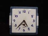 a white clock with blue numbers on it on a black surface