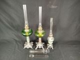 three green glass candlesticks on a clear stand with a black background
