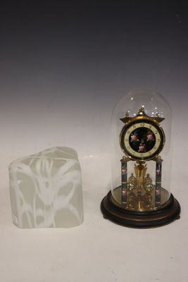 une horloge sous un dôme de verre, à côté d'un bloc de glace