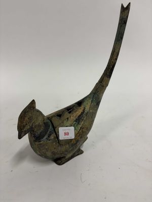une vieille statue d'oiseau en bronze avec une étiquette autour du cou