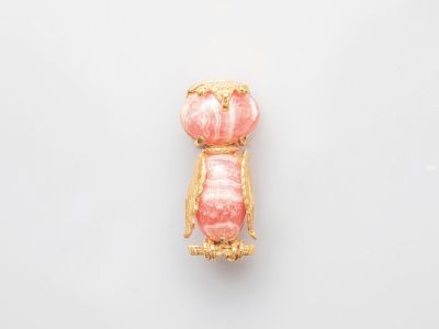 une broche rose et dorée sur un fond blanc