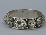 a close up of a silver bracelet on a gray surface