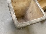a cement pot sitting on the floor next to a cardboard box