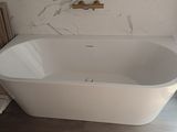 une baignoire blanche installée dans une salle de bains, près d'une fenêtre