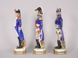 three figurines of men dressed in military uniforms stand in a row