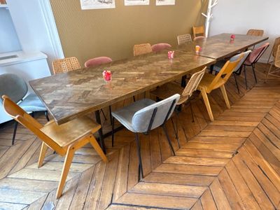 une longue table avec des chaises et un vase posé dessus, dans une pièce