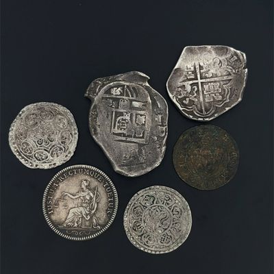 four different types of silver coins on a black surface