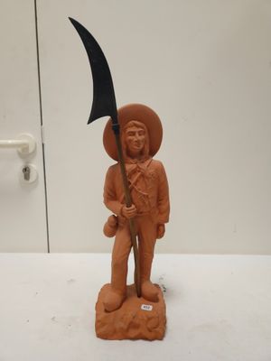 une figurine en argile représentant un homme tenant une faux