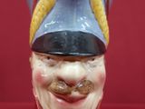 une figurine représentant un homme souriant coiffé d'un chapeau