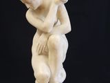 marble statue of a man kneeling on a pedestal with his hands on his knees