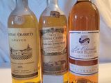 Trois bouteilles de vin sont posées sur une table, accompagnées d'une étiquette de prix