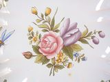 a plate with a flower design on it and a dragonfly