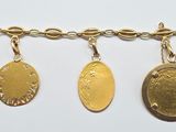 three gold coin charms hanging from a gold chain on a white surface