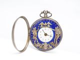 une montre de poche argentée et bleue posée sur une surface blanche