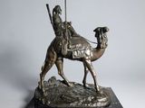 bronze statue of a man riding a camel with a spear on a marble base