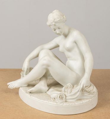 statue d'une femme assise sur un rocher, les jambes croisées