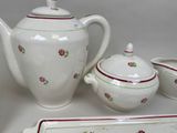a white tea pot with red flowers on it next to a tray and a tray with a tea pot on it