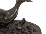 bronze statue of a duck on a rock with a white background