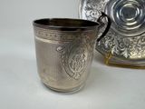 a silver cup sitting next to a silver plate on a table