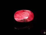a close up of a red ruby stone on a black surface