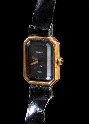 une image représentant une montre-bracelet noire et dorée sur fond noir